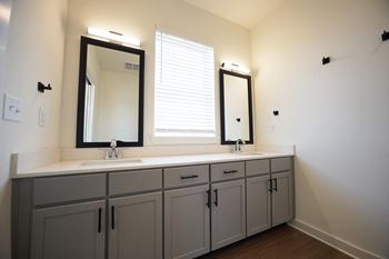 A bathroom with a double vanity and two framed mirrors at Wesley Place Apartments in Birmingham, AL